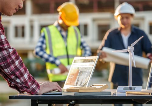 engineers discussing a solar energy project with a small solar panel model on the table, a laptop